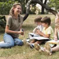 full-shot-smiley-teacher-kids-outdoors